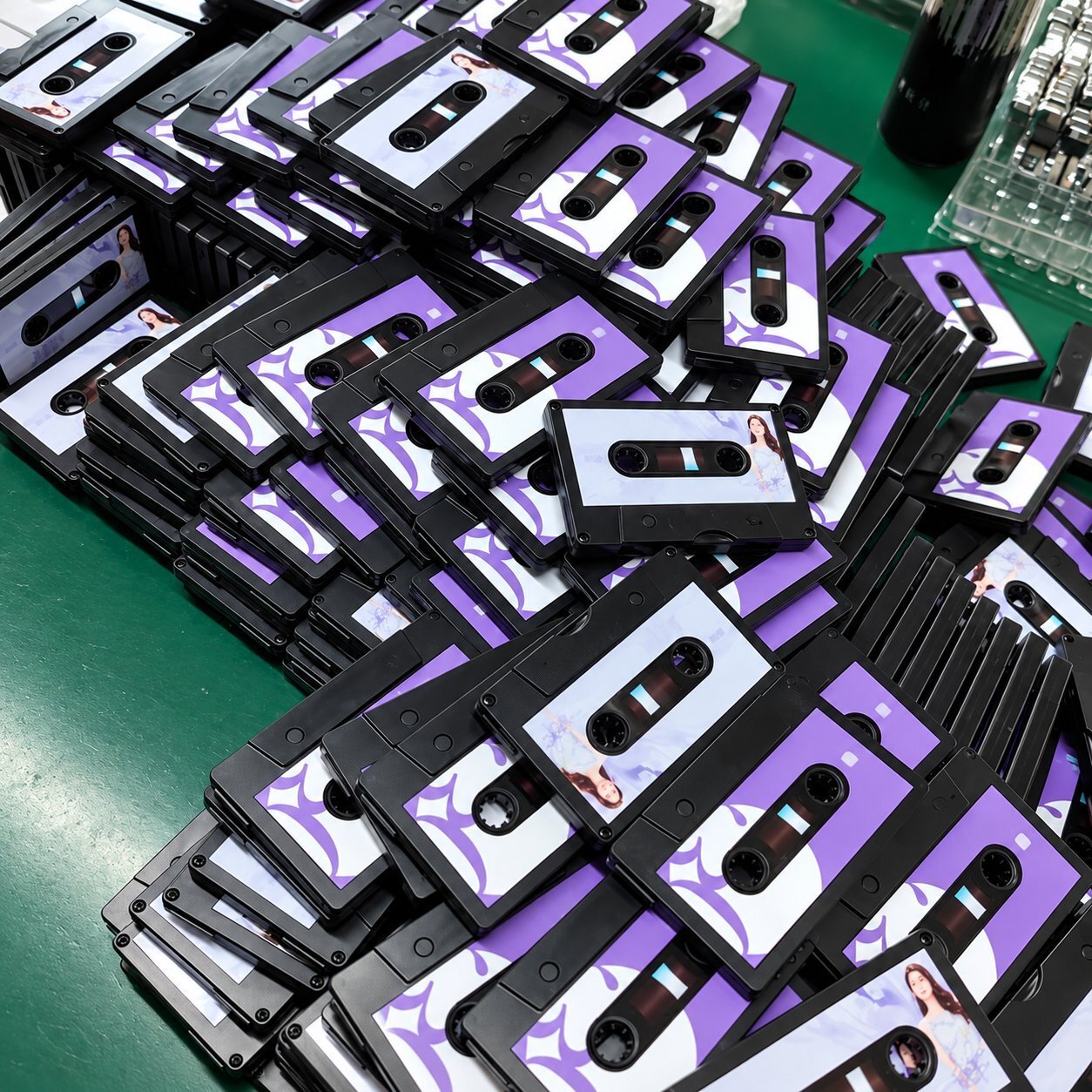 Stacks of cassette-tape shaped custom USB flash drives with a purple label area printed with a stock photo insert, showing how a fully custom-mold shape can imitate a familiar object for branded promotional use.